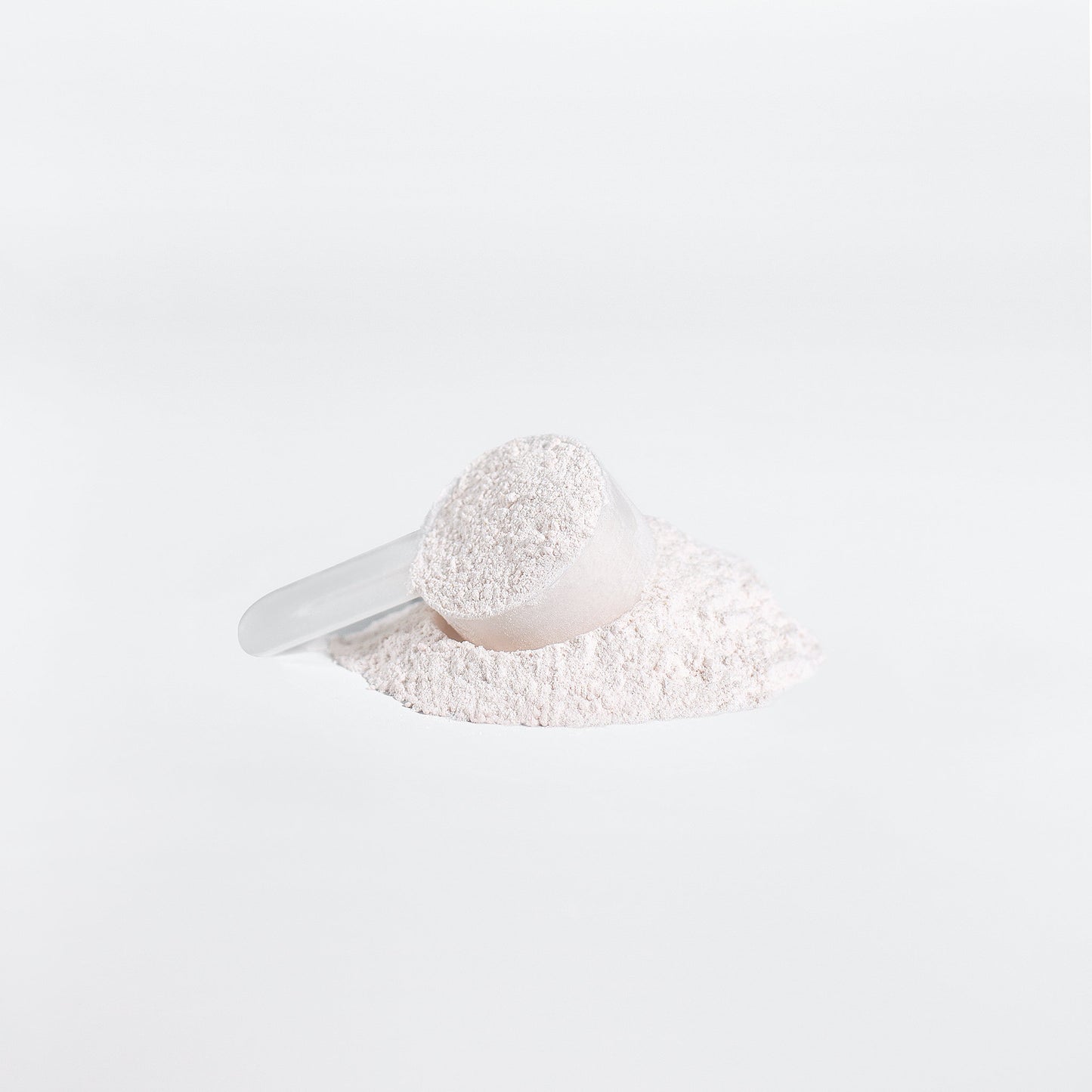 White scoop filled with white powder on a light gray background